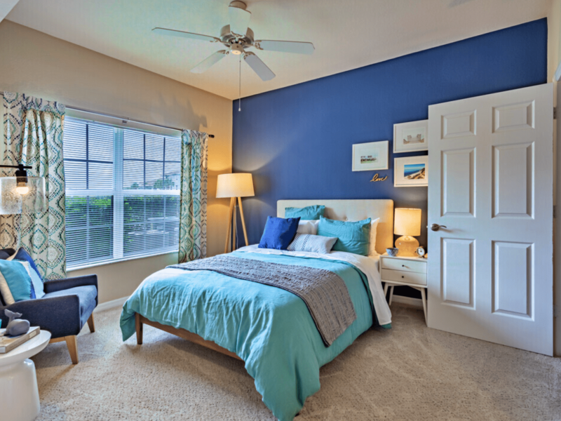This image shows the bedroom area featuring a stylish boudoir chair beside the bedroom and a passageway directly through the living room.